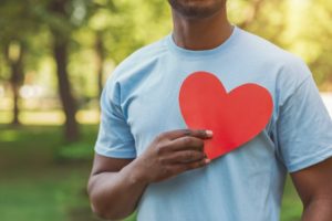 person holding a paper heart up to their chest