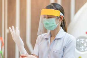 Weatherford dentist with face shield puts on gloves in preparation