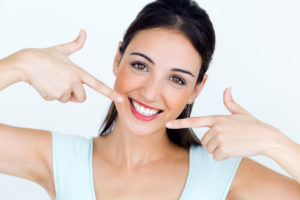 Young woman pointing to healthy beautiful smile