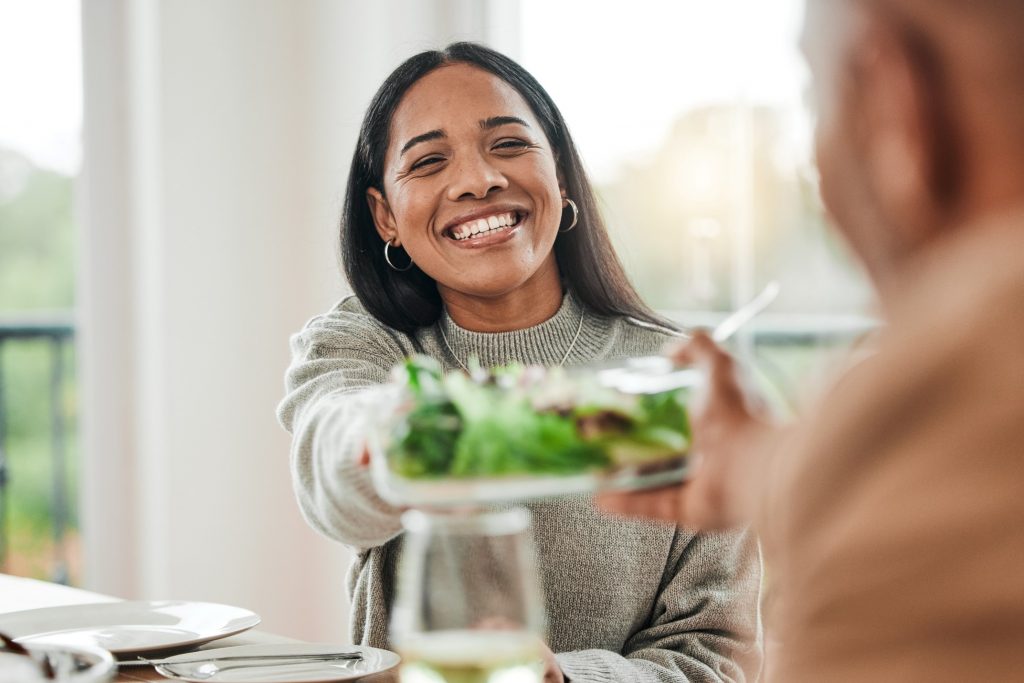 Woman smiling while handing dish to loved one on Thanksgiving