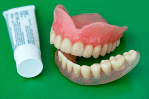 Dentures sitting next to a tube of denture adhesive cream